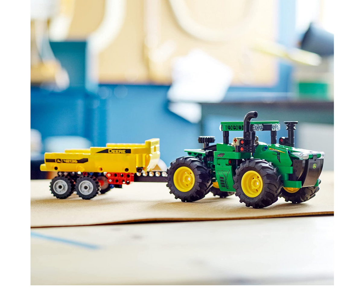 Assembled LEGO Technic John Deere green tractor and yellow trailer on a table
